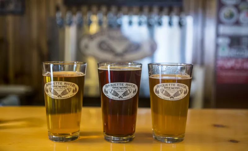 Three beers hand-crafted at Raquette River Brewing aligned on the bar