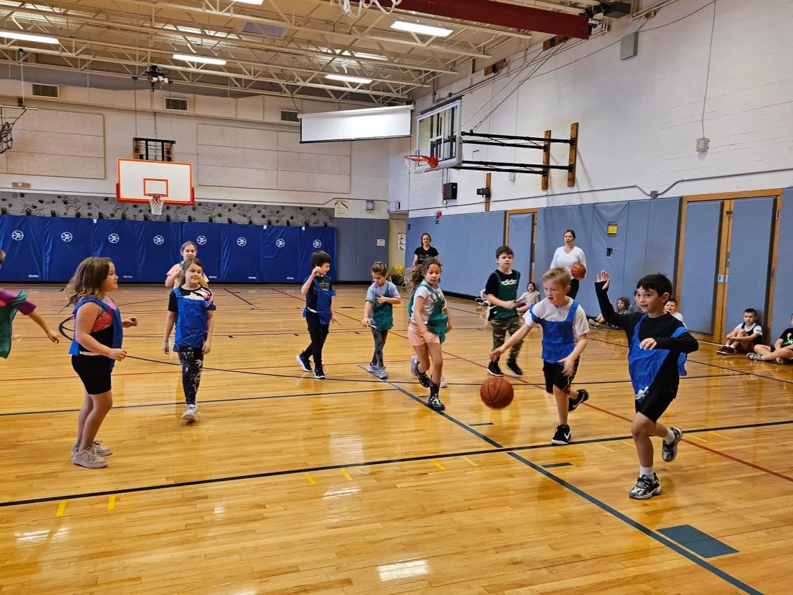 A group of elementary school kids play rec sports in a gym.