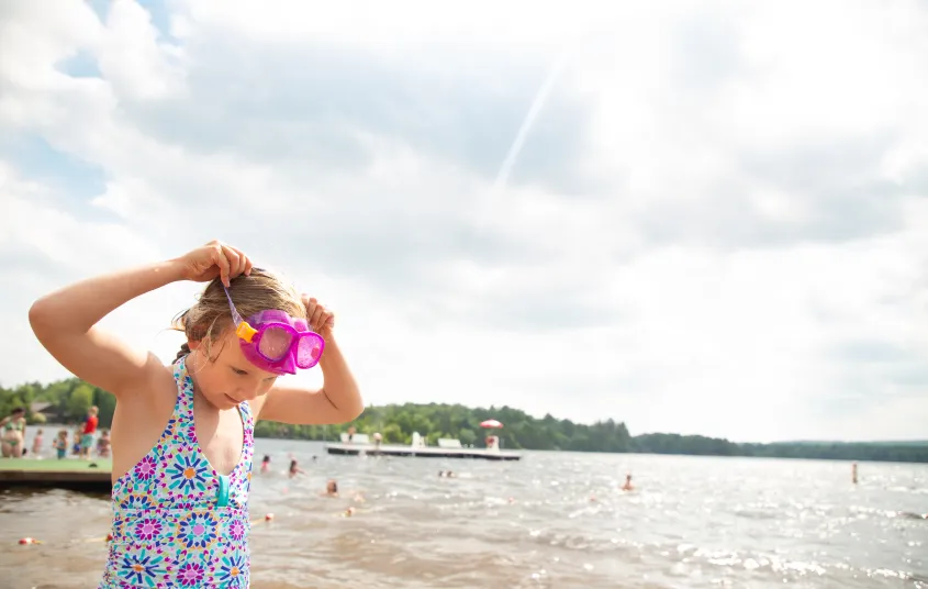 A young girl puts pink goggles on