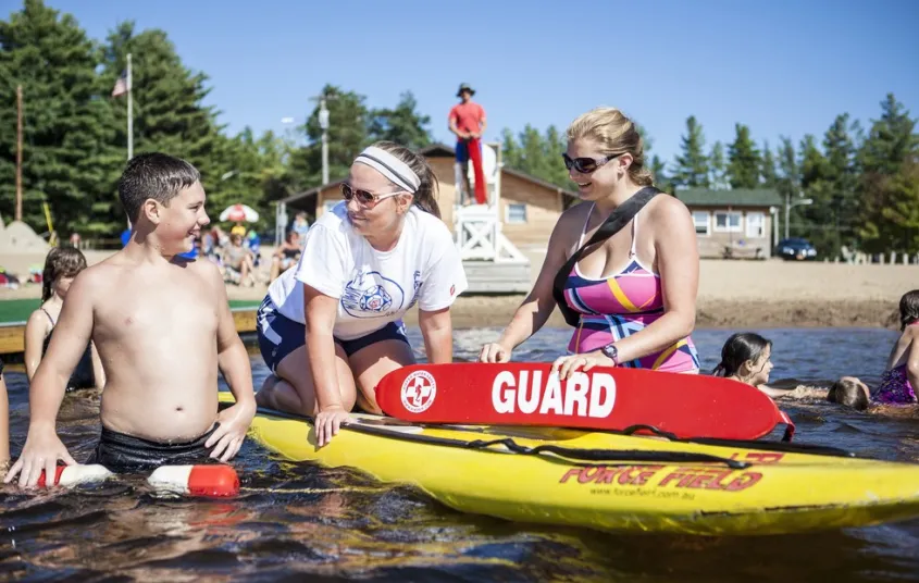 A lifeguard interacts with young beachgoers