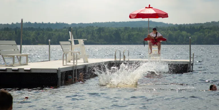Someone jumps into the water from a floating dock