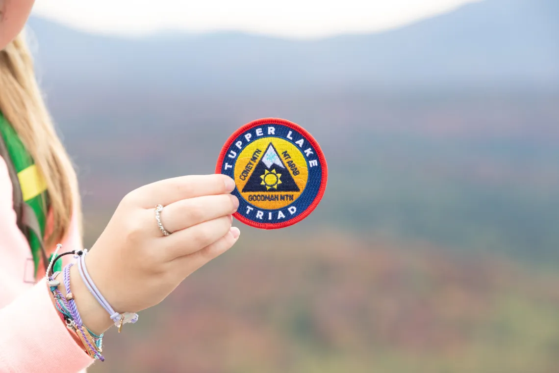 A girl holding a hiking patch