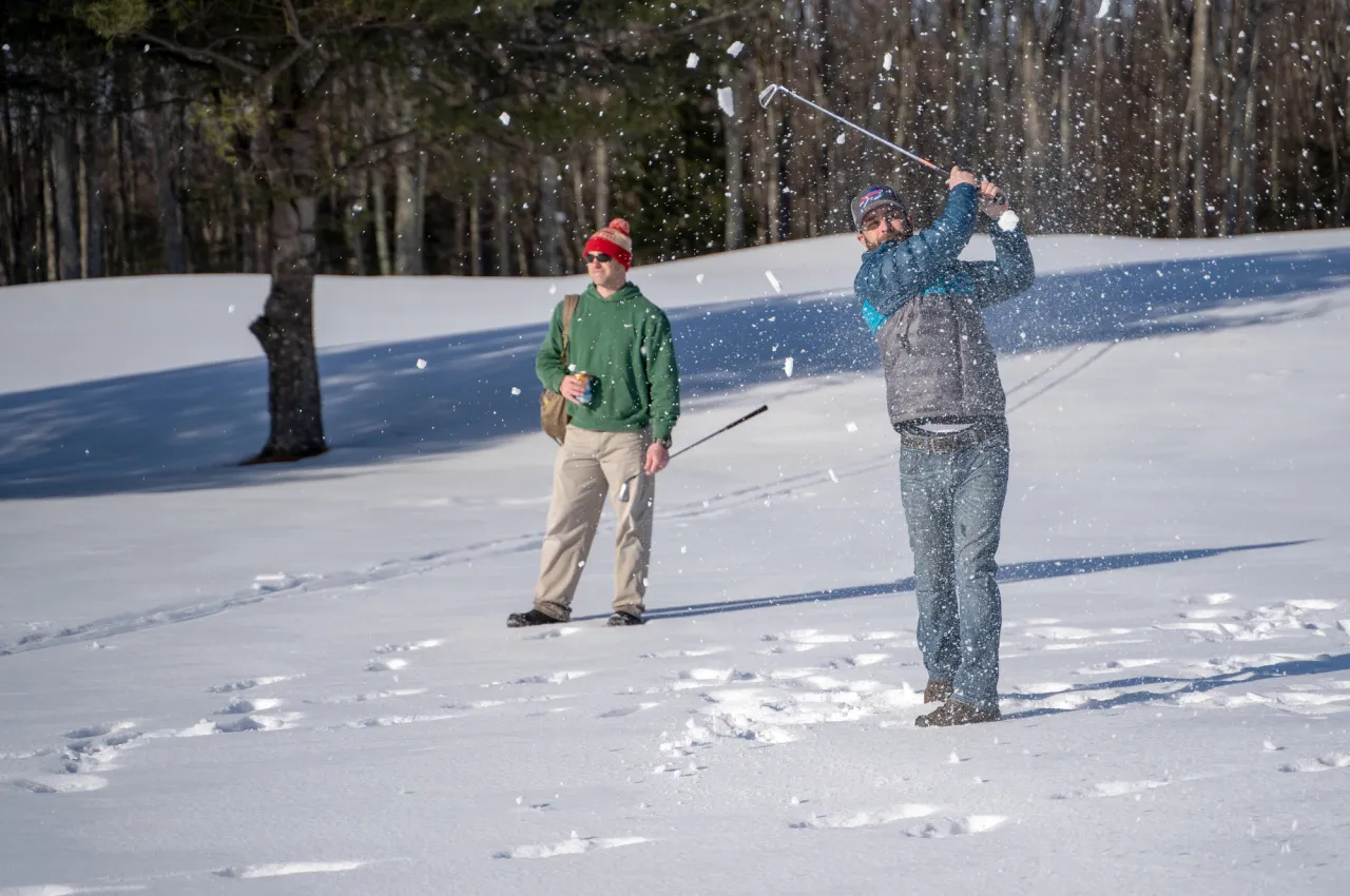 Two men golf in the snow.