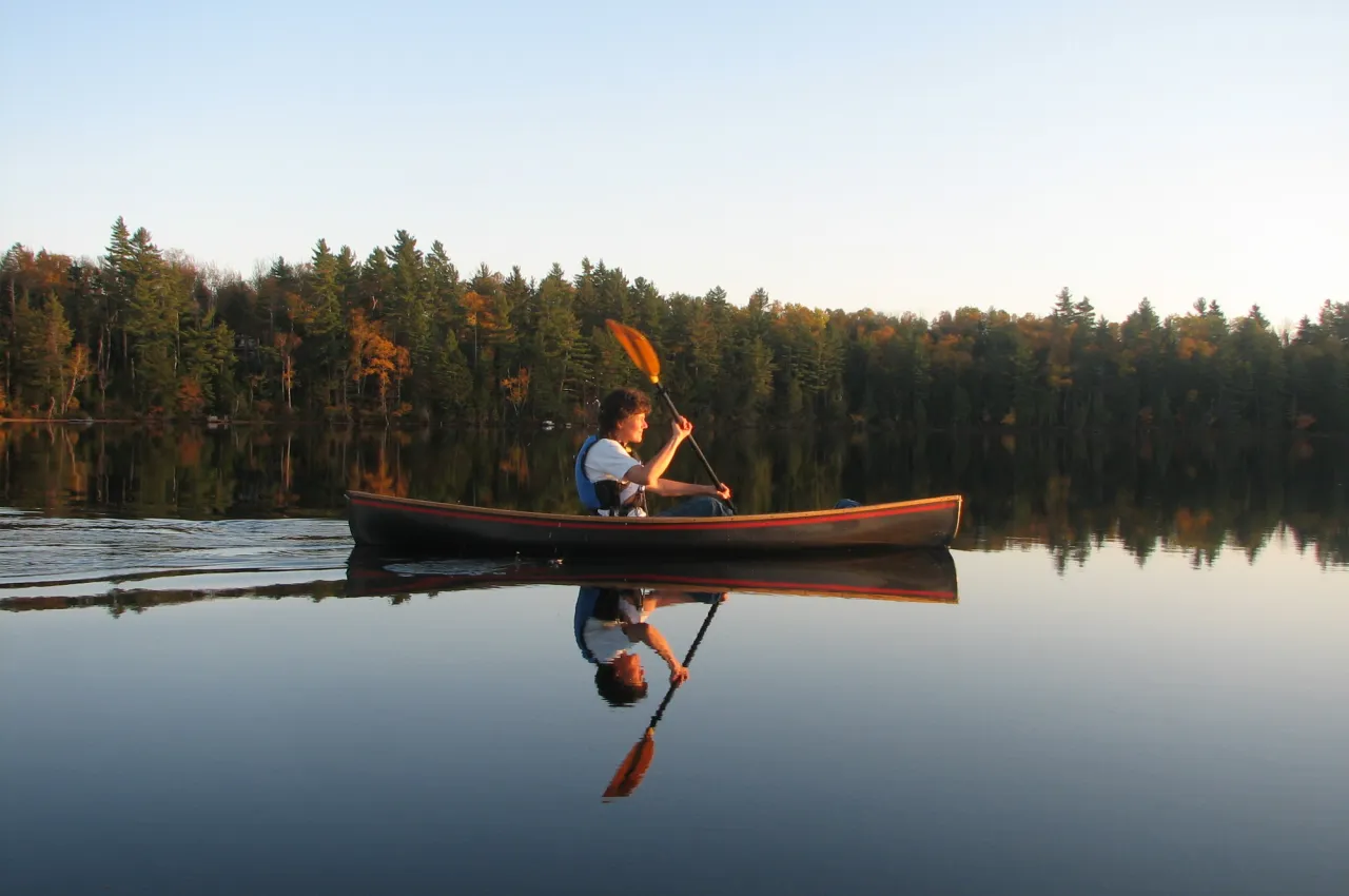 A paddler on a lake during fall.