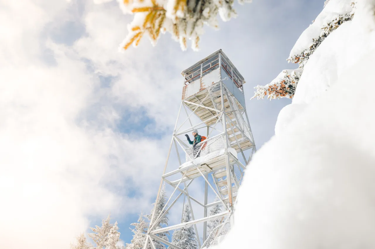 Looking up at a fire tower on a snowy slope.