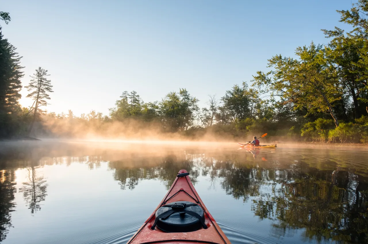 A person kayaking on a lake in Tupper Lake.