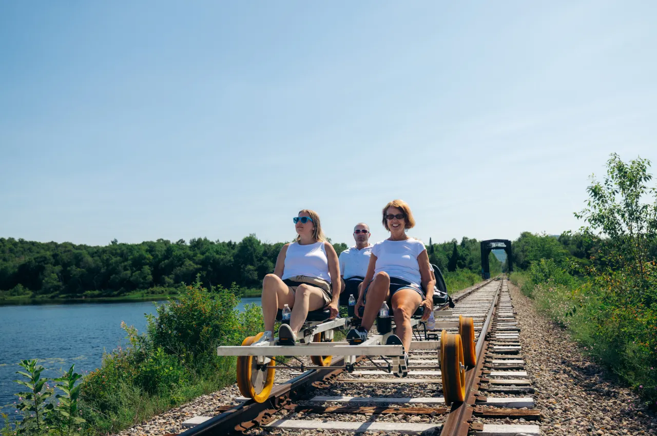 A family rides rail bikes on train tracks in the summer.