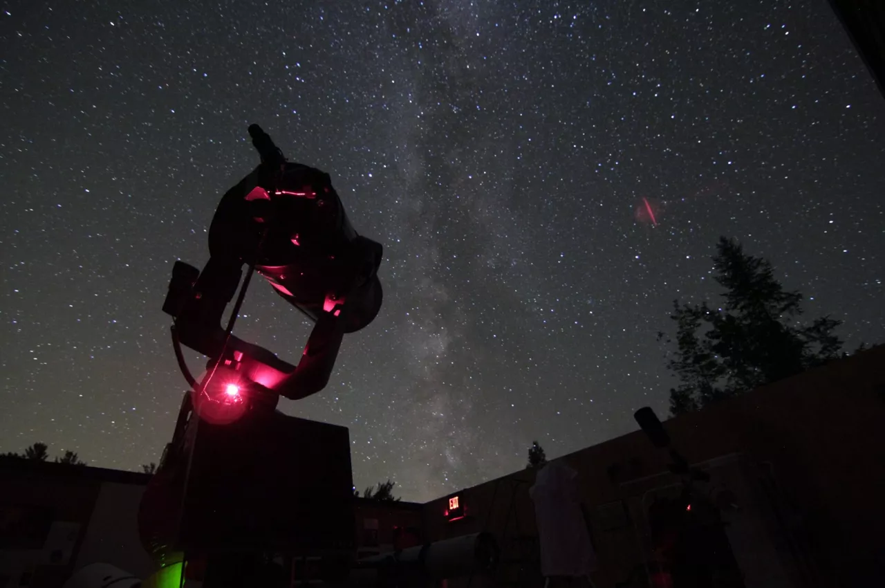 A telescope aims up at the night sky in the roll off roof observatory.