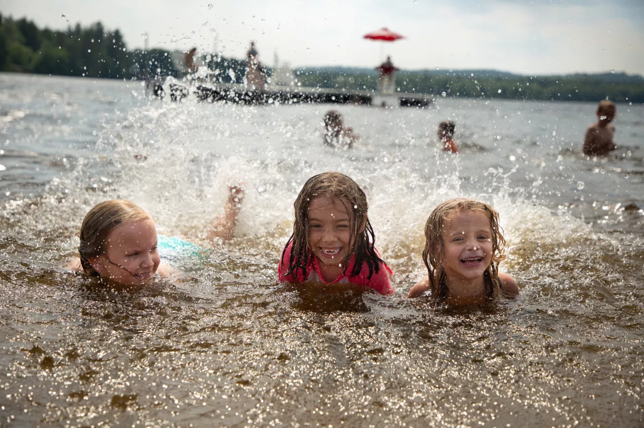 Three girls lay in the water splashing with their feet at Little Wolf Beach