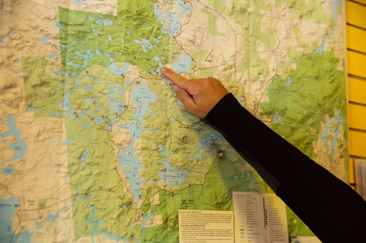 A person's index finger points at a map