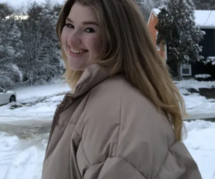 A woman smiles at the camera in a snowy image. 