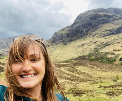 A selfie of a woman with a scenic background.