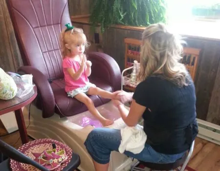 A little girl sits in a pedicure chair.