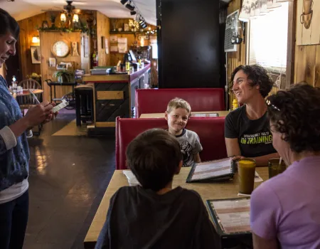 A family sits in a booth with menus.