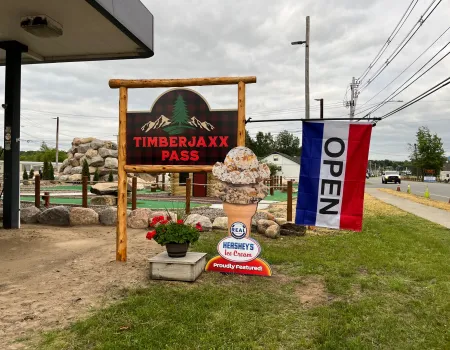 Timberjaxx Pass Ice Cream and Mini Golf shop Tupper Lake Sign with open flag.