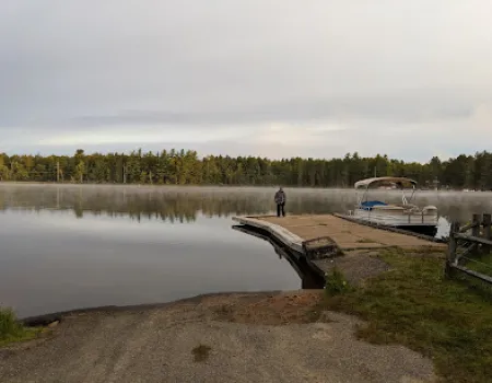 Sturdy boat launch onto a picturesque lake as smooth as glass and ringed with pines