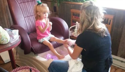 A little girl sits in a pedicure chair.