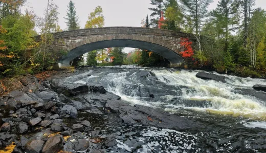 The arching bridge over Bog River Falls