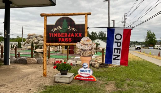 Timberjaxx Pass Ice Cream and Mini Golf shop Tupper Lake Sign with open flag.
