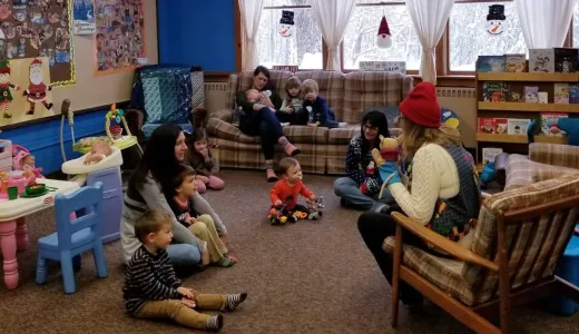 Families sit on the carpet and couches at story time.