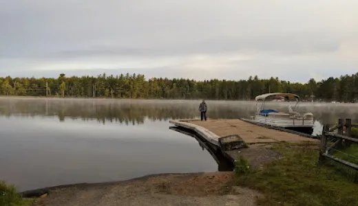 Sturdy boat launch onto a picturesque lake as smooth as glass and ringed with pines