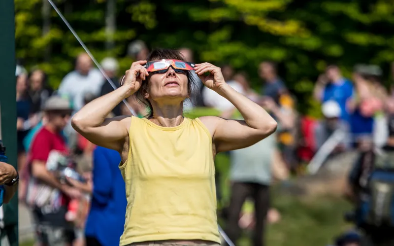 A woman using eclipse glasses to view the sun during an eclipse
