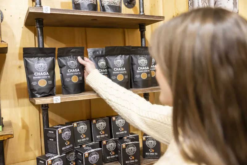 a woman selects Chaga tea on a shelf of Chaga products.