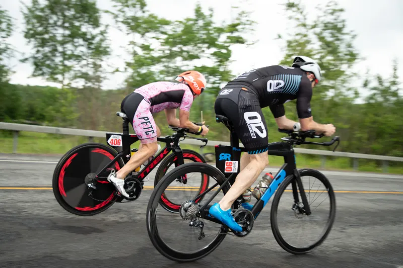 two cyclists race together in full cycling gear.