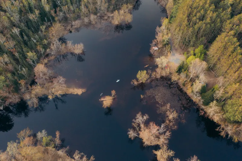 A aerial of a kayaker, a SUP, and a wooden canoe
