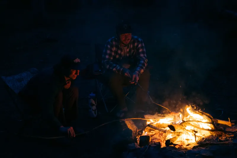 Two campers roast marshmallows in a fire