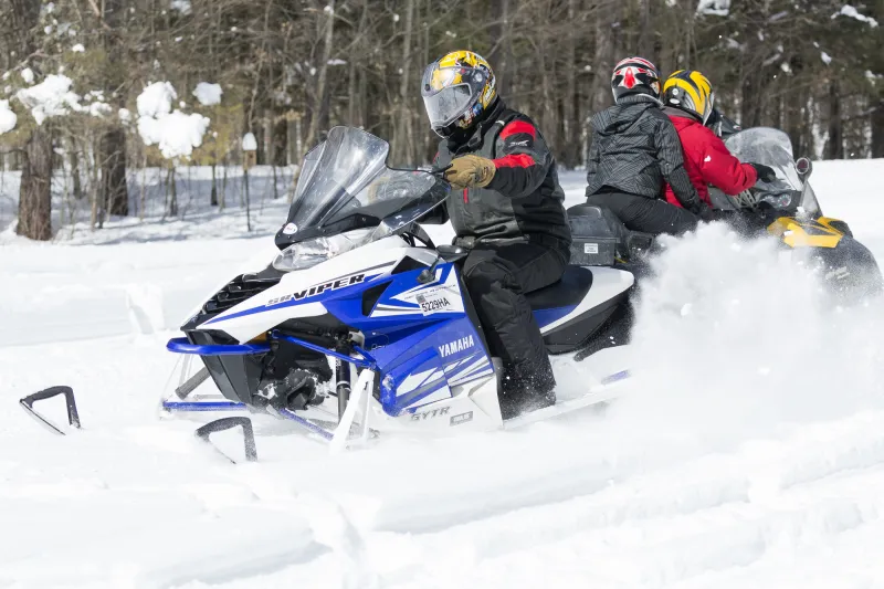 Snowmobilers cross paths on a powdery trails