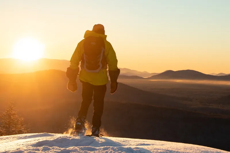 A snowshoer walks along a rocky winter summit