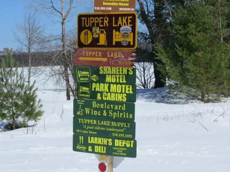 Tupper Lake business signs along the railroad bed. The signs are put up in the winter by the Tupper Lake Snowmobile Club to help riders navigate to local businesses.