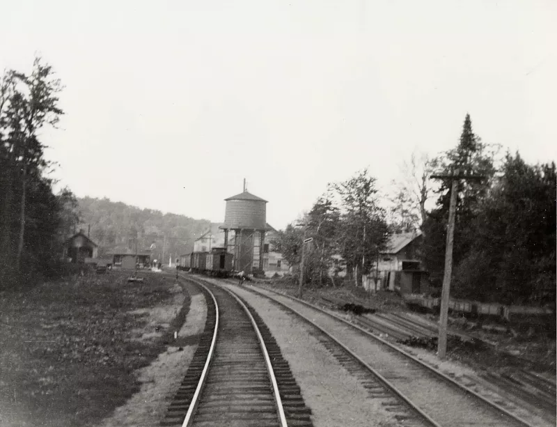 Horseshoe Lake Railroad Station (c. 1900). The image looks north towards the Horseshoe Lake Train Station (left). The building furthest to the left is the two-stall engine house for the Maple Valley RR owned by A.A. Low. On the right are the mill buildings for the Wake Robin RR also owned by Low. (Photo from the Adirondack Museum Collection)