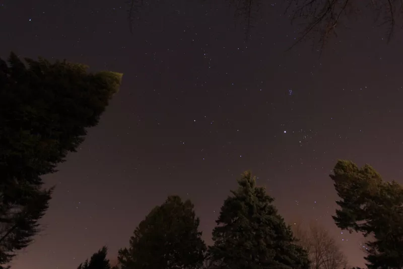 The pink glow here is from light pollution. Photo taken with a DSLR and 10-22mm lens. The brightest "star" is the planet Jupiter, near the cluster of stars known as the Pleiades.
