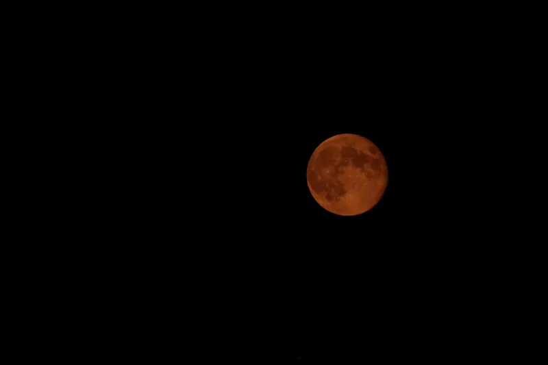 The moon appears reddish orange during a lunar eclipse.