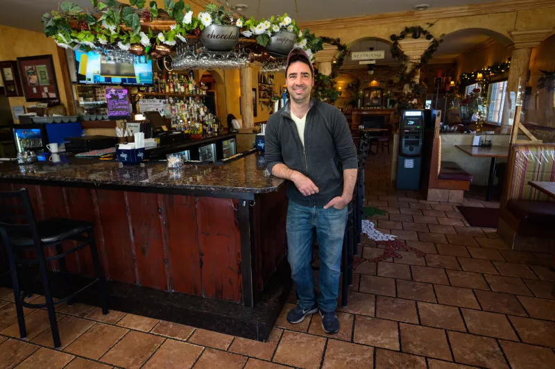 Portrait of Ted Demarais standing in front of his restaurant's bar