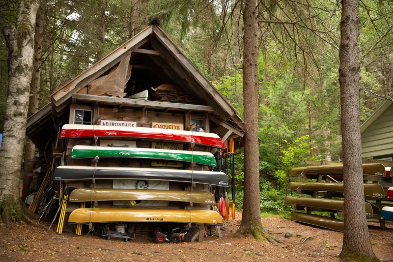 Canoe rentals stacked next to a wooden building.