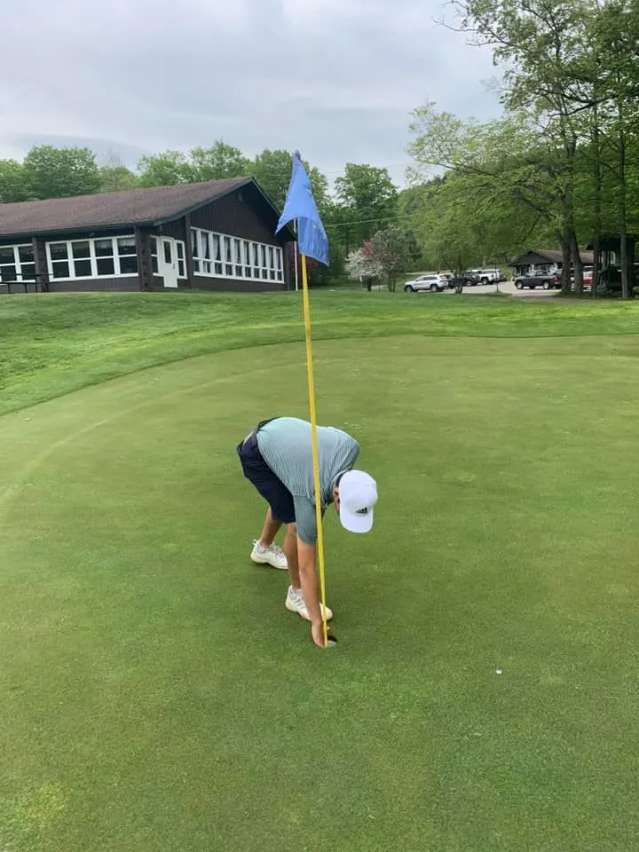 Nick picking his hole in one ball out of the cup on the 18th hole.