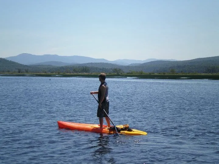 A man paddles on a standup paddleboard with mountains in the background