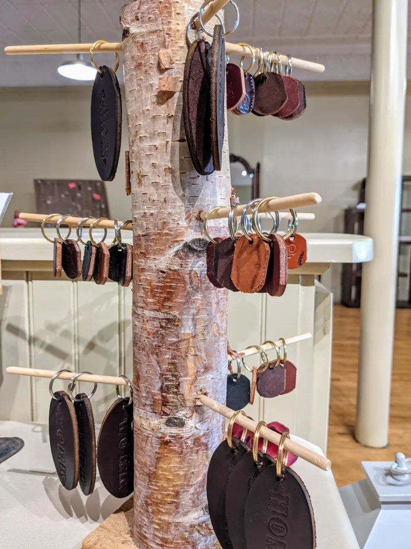 Hand-made leather keychains hang on a birch bark display at Leather Artisan