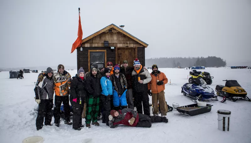 A group of individuals pose together on the ice before enjoying a day of ice fishing.