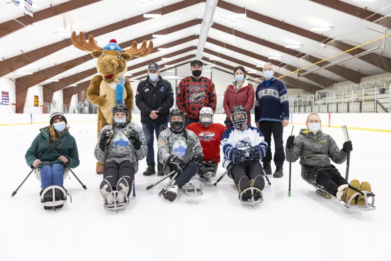 A group of people on sled hockey sleds and ESWG staff standing in the background.