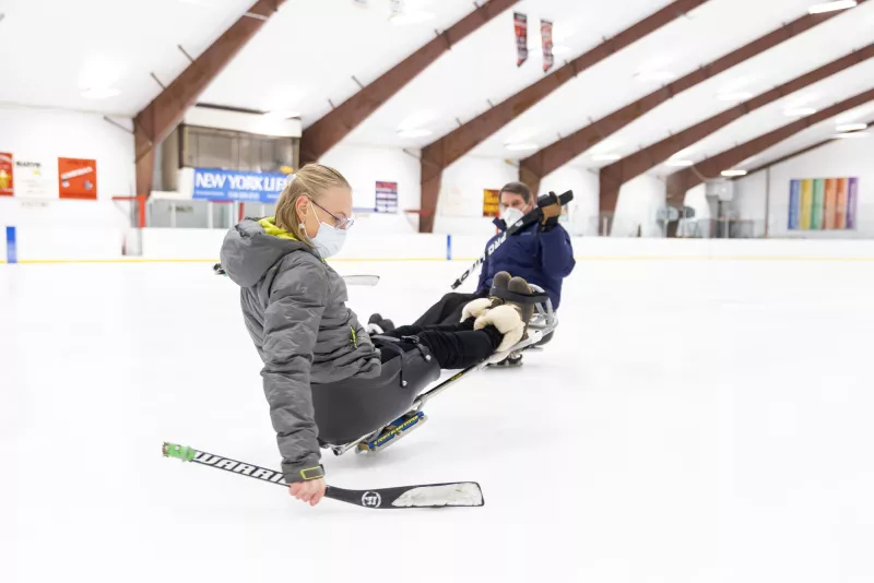 Woman practicing balance on a sled hockey sled
