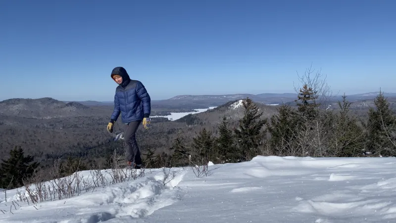 The author walks on the summit of Coney Mountain. Goodman Mountain and Tupper Lake loom in the background