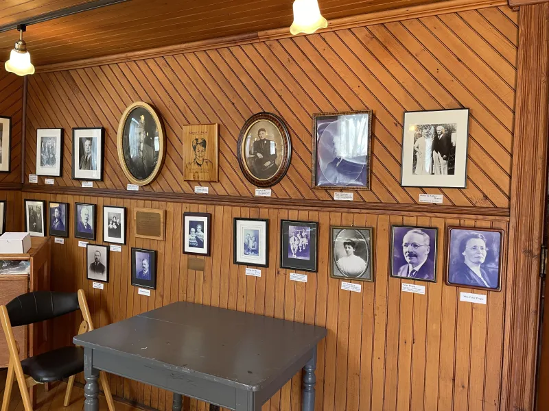 A display of framed black and white photos on a wood paneled wall.
