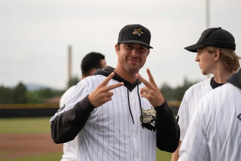 A baseball player in uniform gives two peace signs to the camera.