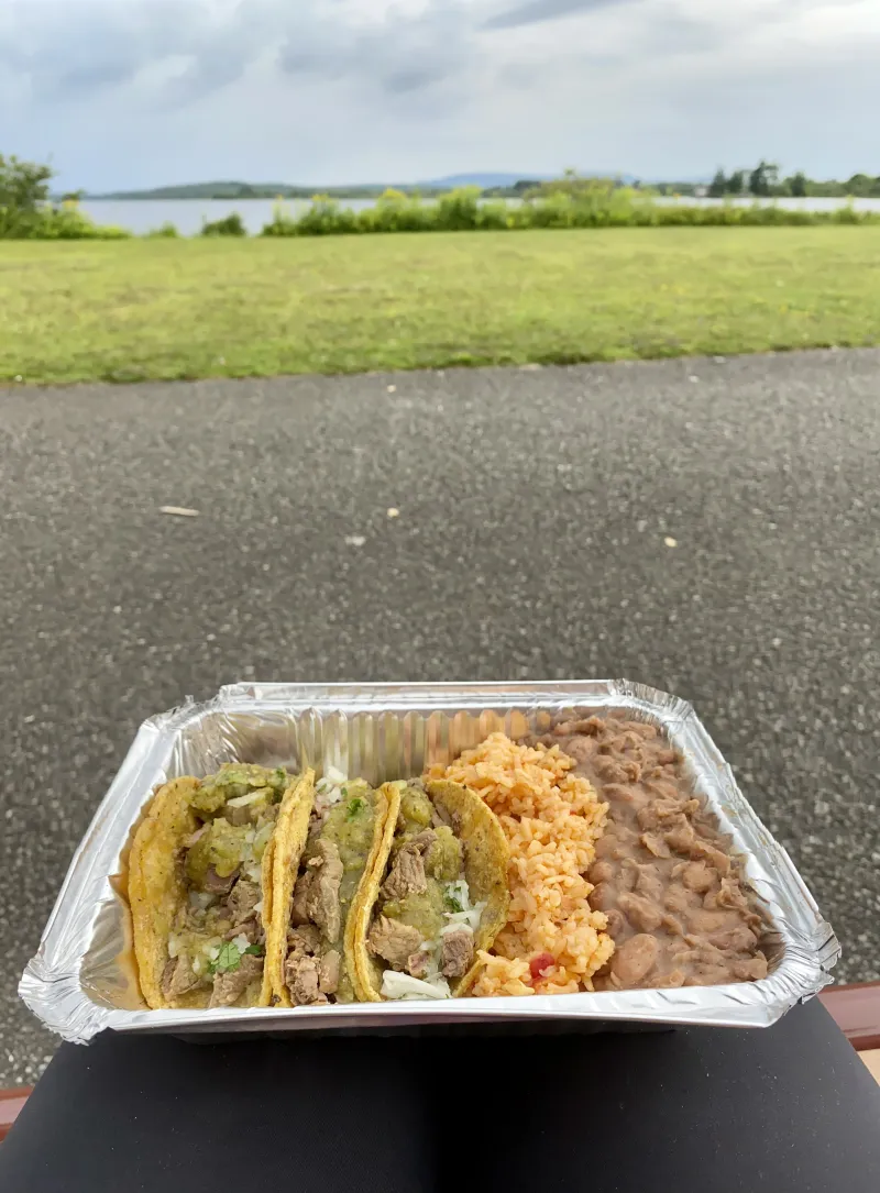 Tacos, rice, and beans from Dos Loco Gringos with a lake and trees in the background.