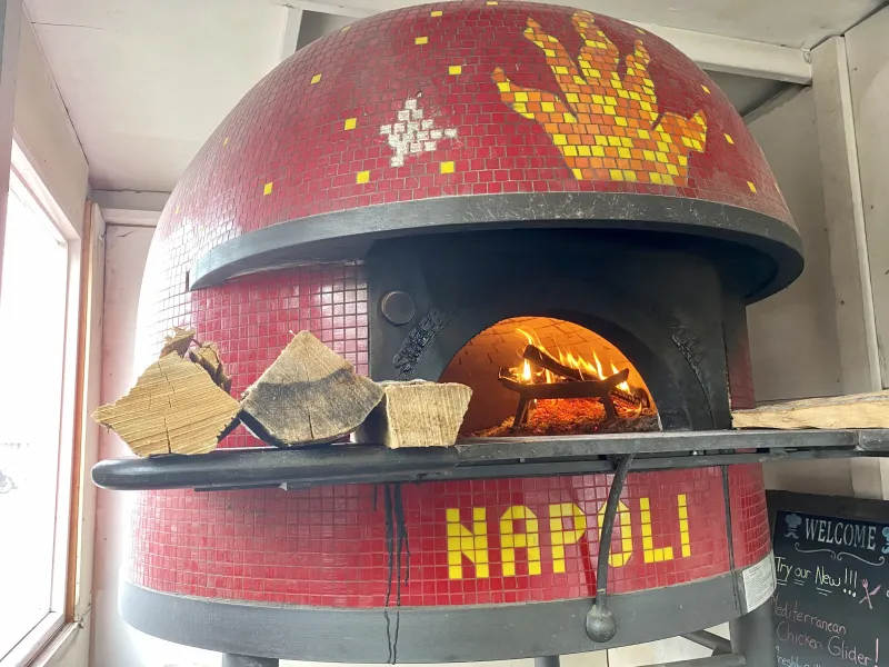 Fire inside a brick oven cooking pizza.