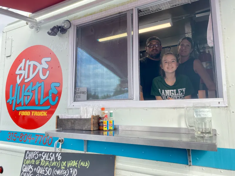 Team of three working and smiling in a food truck.